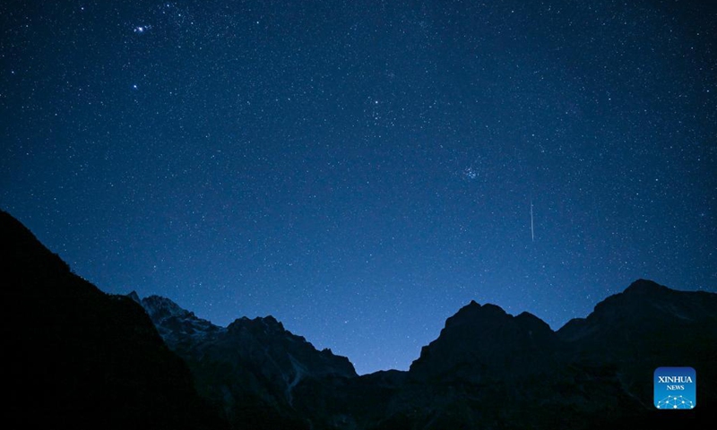 Photo taken on Dec. 14, 2021 shows a meteor of Geminids meteor shower at the Yulong Snow Mountain in Lijiang City, southwest China's Yunnan Province. The Geminids meteor shower of 2021 reached its peak on Tuesday.(Photo: Xinhua)