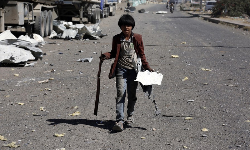 A boy is walking on a street covered with debris of a destroyed warehouse in Sanaa, Yemen on Dec. 16, 2021. (Photo: Xinhua)