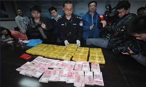 Police in Anyi county, Jiangxi Province check drugs and cash seized from a drug user's home on Sunday. Police from Jiangxi and Yunnan provinces jointly raided a drug trafficking gang on March 24, arresting eight suspects and confiscating more than 120,000 pills along with several million yuan in cash. Photo: IC