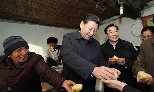 Xi Jinping (C), general secretary of the Communist Party of China (CPC) Central Committee and chairman of the CPC Central Military Commission, tastes steamed potatoes while visiting the family of Tang Rongbin (back), an impoverished villager in the Luotuowan Village of Longquanguan Township, Fuping County, north China's Hebei Province, Dec. 30, 2012. Xi made a tour to impoverished villages in Fuping County from Dec. 29 to 30, 2012. Photo: Xinhua