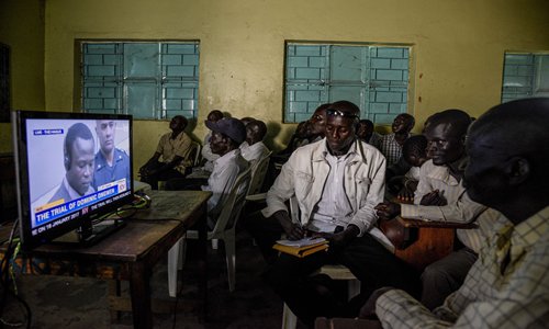 People watch on TV the screening of the start of the International Criminal Court trial of former child soldier-turned-warlord Dominic Ongwen in Lukodi, Uganda on Tuesday. Photo: AFP