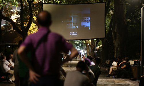 People stand or sit on stools to watch outdoor movies shown at Shanghai's parks. Photos: Yang Hui/GT