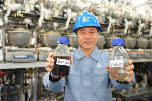 An employee of Sinopec Group holds the biofuel and cooking oil (right hand) to make a comparison. Photo: Courtesy of Sinopec Group