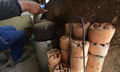 Center: A resident heats water on a coal-burning stove. Photo: VCG