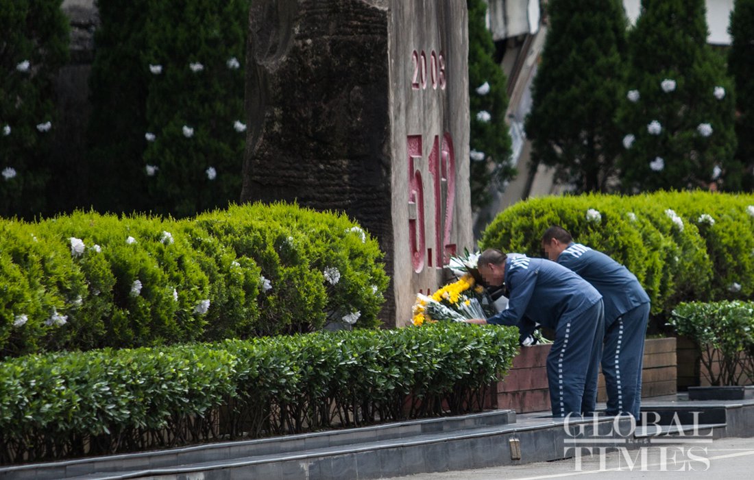 Accompanied by prison officers, two prisoners place flowers for their relatives who died in the Wenchuan earthquake in the Memorial Cemetery on May 11. Photo: Li Hao/GT