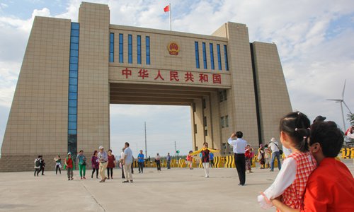 Wang Ying and her granddaughter Mengmeng, tourists from Central China's Hubei Province, view the national gate at Alashankou, Northwest China's Xinjiang Uyghur Autonomous Region, on August 2. China-Europe freight trains pass beside the gate every day. Photo: Shan Jie/GT
