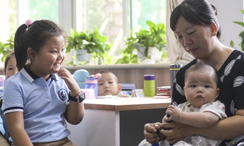 A mother holds her second child and accompanies her elder daughter to her first class of a new semester of the Primary School Affiliated to Shandong Normal University in Ji'nan on September 3. Photo: VCG