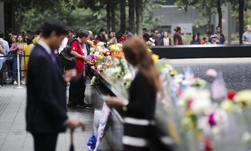People pay tribute to victims beside plates on which the names of 9/11 victims were inscribed around the North Pool at the National September 11 Memorial and Museum in New York, the United States, Sept. 11, 2018. Thousands of people came here on Tuesday to memorize the victims of the 9/11 terror attacks which happened 17 years ago and claimed thousands of lives. (Xinhua/Wang Ying)