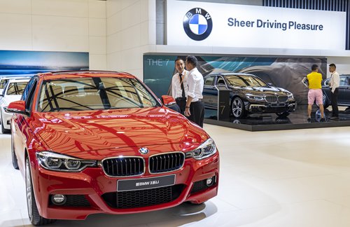 Employees look at a BMW car at an auto show in Shanghai on September 28. Photo: VCG