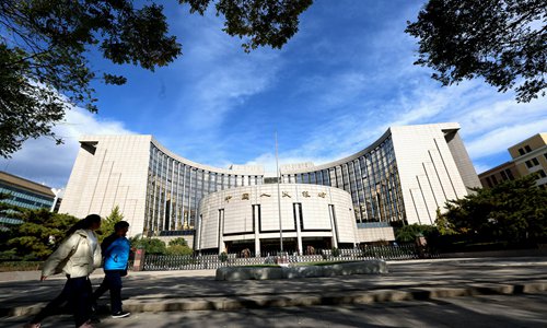 People pass by the People's Bank of China in Beijing. Photo: VCG