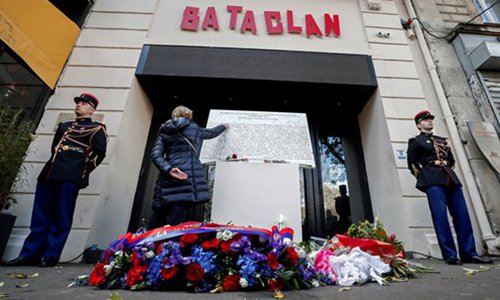 A woman touches the commemorative plaque at the entrance of the Bataclan concert hall in Paris on Tuesday, during a ceremony held for the victims of the Paris attacks of November 2015, which targeted the Bataclan and a series of bars, killing 130 people. Photo: AFP

