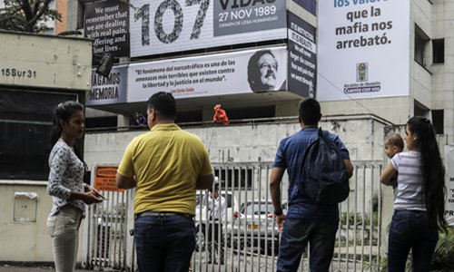 People remain outside as men work at the Monaco building, which was once home to Colombian drug lord Pablo Escobar, and has been covered with pictures of victims of his Medellin cartel, in Medellin, Colombia, on Tuesday.  Photo: AFP