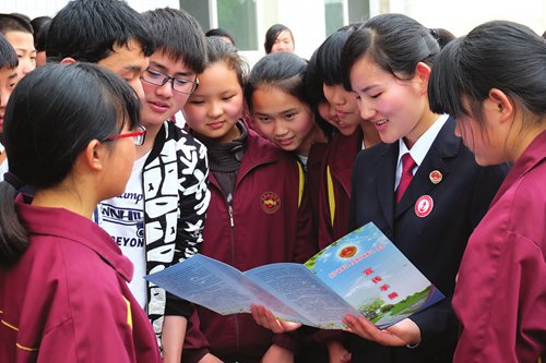 A procuratorate employee in Changde, Central China's Hunan Province reads a brochure on preventing juvenile crime to local middle school students on April 23, 2015. Photos: CFP