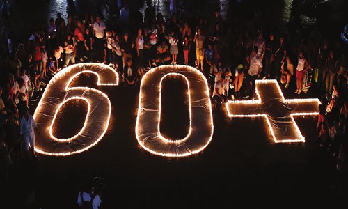 People light candles and form the 60+ sign on Saturday in Cali, Colombia at an Earth Hour organized by the green group WWF. Earth Hour is a global call to turn off lights for one hour in a bid to highlight global climate change. Photo: AFP
