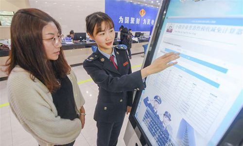 A staff (R) explains to a taxpayer about a new policy on VAT reduction at a local tax bureau in Fengze District of Quanzhou, southeast China's Fujian Province, April 1, 2019. Starting on April 1, companies that are subject to the 16-percent VAT rate on their taxable sales or imported goods will enjoy a 13-percent VAT rate, while those who are subject to the 10-percent VAT rate will only need to pay 9 percent, reads a Ministry of Finance statement. (Photo:Xinhua)