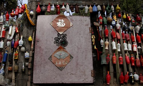 Colorful used Baijiu bottles are strung together to form part of a wall at the entrance of a house in Mentougou district in suburban Beijing. Photo: VCG