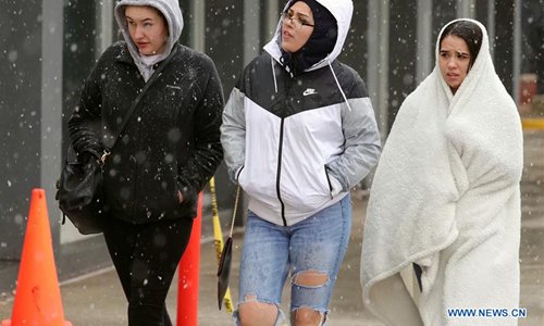 People walk amid snow at downtown Chicago, the United States, on April 27, 2019. A rare late snowstorm swept across Chicago on Saturday.  (Photo: Xinhua)