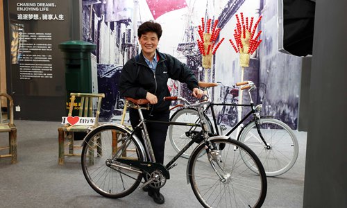 A woman poses with a Chinese-branded bicycle at the Shanghai Exhibition Center during the China Brand Day event on Friday. Photo: IC