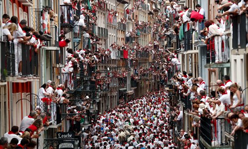 Runners try to avoid bulls as they run down a street during the traditional San Fermin bull run in Pamplona, Spain, on Sunday. The festival, locally known as Sanfermines, is held annually from July 6 to July 14 in commemoration of the city's patron saint. Hundreds of thousands of visitors from all over the world attended the fiesta. Photo: IC