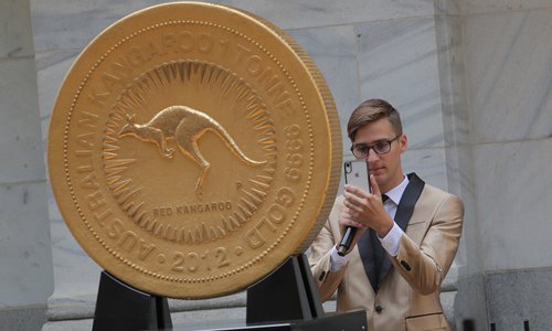 A man takes a photo of the world's largest gold bullion coin, the Australian Kangaroo One Tonne Gold Coin, which is being displayed to mark the official launch of the Perth Mint Physical Gold Exchange Traded Fund (AAAU), outside the New York Stock Exchange (NYSE) in New York, US, on Wednesday.. Photo: VCG