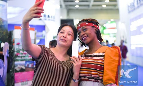 A visitor takes selfies with a staff member at the booth of Uganda during the China-Africa Economic and Trade Expo in Changsha, central China's Hunan Province, June 28, 2019. The exhibition hall of the expo opened to public on Friday and Saturday. (Xinhua/Xue Yuge)