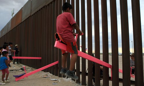 American and Mexican families play with a toy called “up and down” (seesaw swing) over the Mexican border with the US at the Anapra zone in Ciudad Juarez, Mexico on Sunday. Photo: AFP