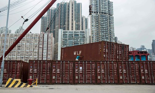 A worker assists shipping containers as they are stacked on a pier in Hong Kong in October 2018. Photo: VCG