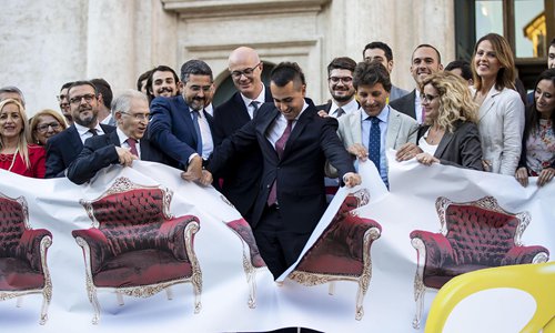 Italian Foreign Minister Luigi di Maio (center) rips a banner with photos of the armchairs exhibited by M5S parliamentarians in front of the Chamber of Deputies after the launch of the reform that reduces the number of parliamentarians in Rome on Tuesday. Photo: IC