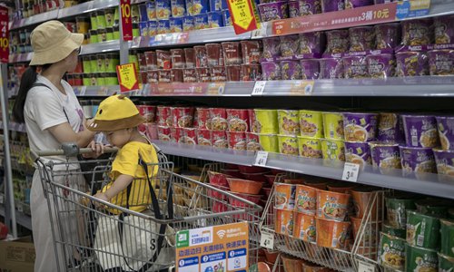 A mother is purchasing packets of instant noodles at a supermarket with her son. Photo: IC