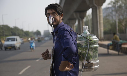 Pankaj Kumar is seen in Noida, on the outskirts of Delhi, India, on Dec. 1, 2019. In the highly polluted Indian capital that witnessed an alarming increase in air pollution recently, a young man named Pankaj Kumar wearing an oxygen mask and carrying a 20-liter plastic water bottle strapped to his back is an unusual attraction. (Xinhua/Javed Dar)