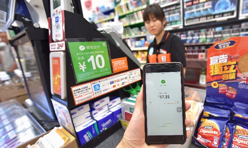 A journalist experiences the mobile payment tool of Wechat Pay at a 7-Eleven convenience store. Photo: Xinhua