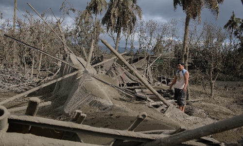 A man stands before the remains of his home covered in ash following the eruption of the Taal Volcano, in Buso Buso, the Philippines on Monday. The volcano eruption in the Philippines has inflicted significant damage on the livelihoods of tens of thousands and is expected to cause more. Photo: AFP
