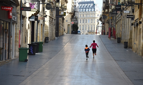 A woman and her son run in the deserted Sainte-Catherine street in Bordeaux, southwestern France, on Thursday, on the third day of a strict lockdown in France to stop the spread of COVID-19, caused by the novel coronavirus. Photo: AFP