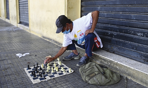 Salvadorean Luis Angel Carcamo, 60, who is homeless, wears a protective mask against the spread of the novel coronavirus as he plays chess against himself on a street of the historic center of San Salvador, El Salvador on Saturday. Photo: AFP