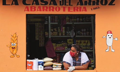 A woman wears a face mask and gloves as she waits for customers at a store in Tegucigalpa, Honduras on Wednesday, amid the new coronavirus pandemic. Honduran authorities confirmed 510 cases of COVID-19 and 46 deaths from it. Photo: AFP