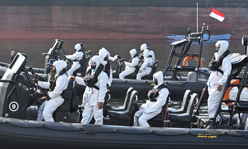 Elite Indonesian navy frogmen wearing protective gear keep watch on their boats as over 300 Indonesian crew members of the Explorer Dream cruise ship are brought ashore for testing and quarantine amid the coronavirus pandemic, at a port in Jakarta on Wednesday. The country has reported 9,511 cases of infection, with 773 deaths. Photo: AFP