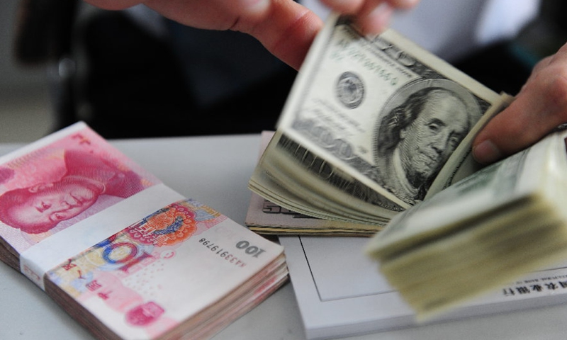 A teller counts U.S. dollar bills at a bank in Qionghai, south China's Hainan Province.Photo:Xinhua