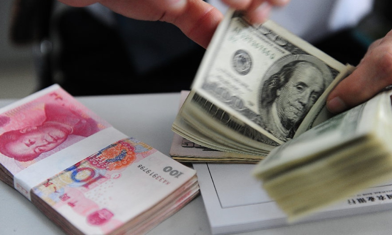 Un caissier compte les billets en dollars américains dans une banque de Qionghai, dans la province de Hainan, dans le sud de la Chine.Photo:Xinhua