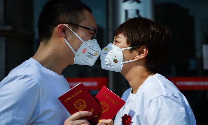 A couple kiss each other and show their marriage certificate on Wednesday, May 20, which is considered China's second unofficial Valentine's Day after Western Valentines. At the civil affairs bureau in Beijing's Chaoyang district, nearly 400 couples registered for marriage. The numbers 