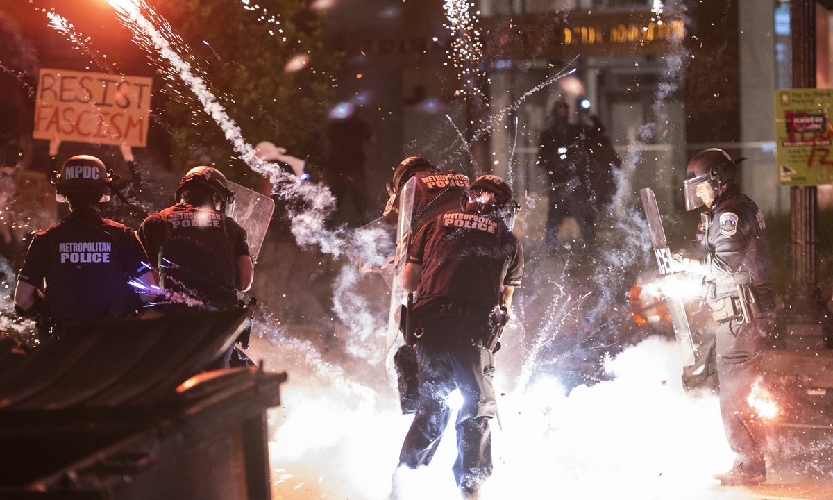 A firecracker thrown by protesters explodes under police one block from the White House on Saturday local time in Washington DC during a demonstration against police brutality in the death of George Floyd, an unarmed 46-year-old African-American man who died on May 25 evening in Minneapolis, Minnesota, after a police officer kneeled on his neck for several minutes. Clashes broke out and major cities imposed curfews as the US began another night of unrest Sunday with demonstrators ignoring warnings from President Donald Trump that his government would stop violent protests 