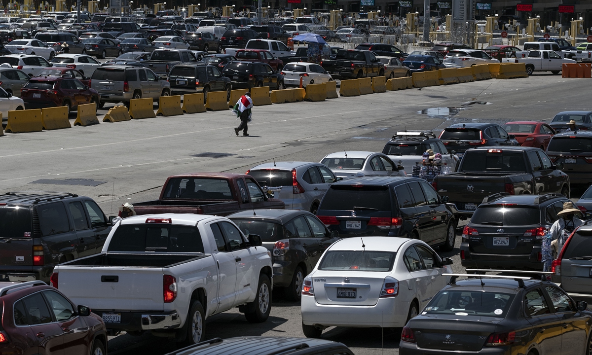 Commuters queue up to cross into the US at the San Ysidro crossing port in Tijuana, Mexico on Tuesday amid the COVID-19 pandemic. Officials from both countries confirmed Tuesday that travel restrictions on nonessential crossings at the US-Mexico border will be extended an additional month. Photo: AFP