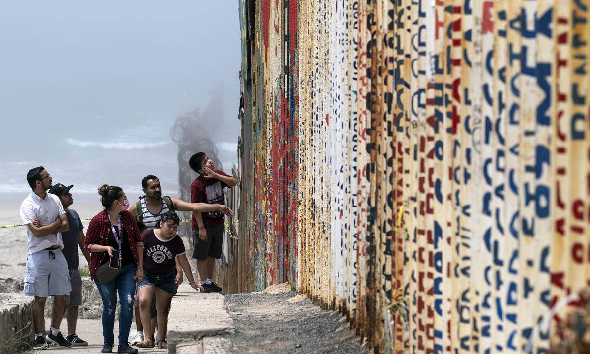A family walks near the US-Mexico border fence in Playas de Tijuana, Baja California state, Mexico on Sunday amid the COVID-19 pandemic. Photo: AFP