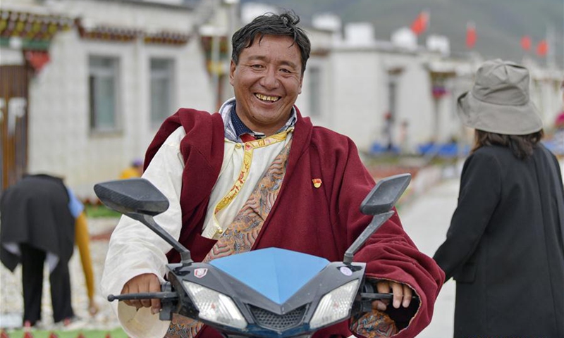 A villager rides an electric motor in the Caiqutang relocation village in Yangbajain Township, Damxung County, southwest China's Tibet Autonomous Region, Aug. 2, 2020. Relocation for poverty-relief purposes carried out in recent years has helped boost rural revitalization in Tibet Autonomous Region. For instance, the Caiqutang relocation village, which saw its first resettlers in late 2017, now offers better utilities and health care to 683 inhabitants who moved from less amiable alpine areas. The relocated residents are also allotted dividends from Yangbajain's hot-spring tourism revenue. Some have joined agricultural collectives which provide job opportunities with decent income. (Xinhua/Zhang Rufeng)