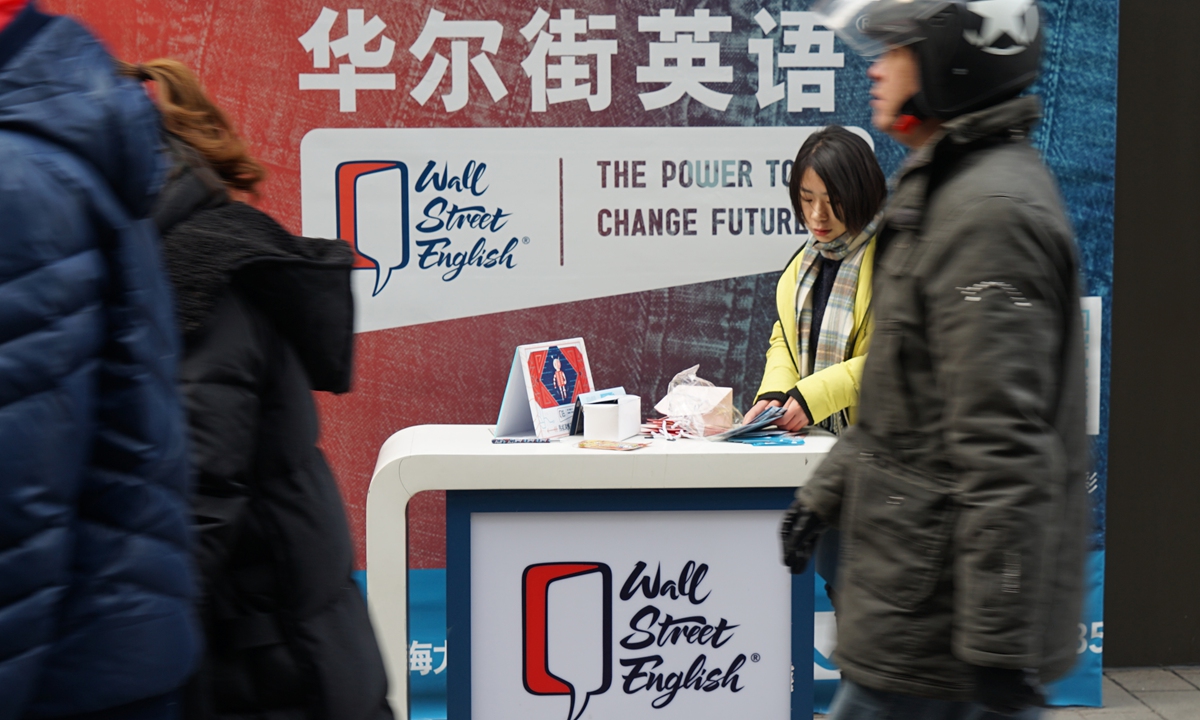 Pedestrians walk past a street stall for Wall Street English in Shanghai. File photo: IC