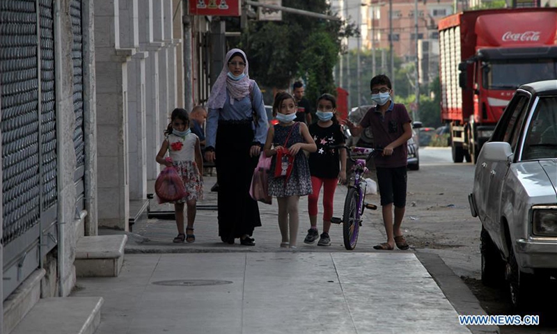 Palestinians wearing face masks walk on a street in Gaza City, during the lockdown to contain the spread of COVID-19, on Sept. 5, 2020. Palestine on Saturday recorded seven new death cases of the novel coronavirus, bringing the total number of deaths to 199. (Photo by Rizek Abdeljawad/Xinhua)