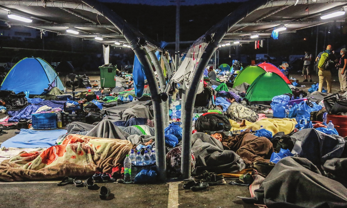 Migrants find shelter at a supermarket parking lot on Thursday on the Greek island of Lesbos before police begin an operation to rehouse thousands of homeless migrants at a new site. The move follows the destruction of their camp by fire a week ago.  Photo: AFP