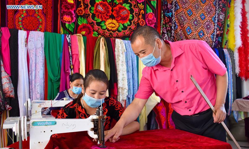 A man guides a staff member in embroidery works at a handicraft making cooperative in Aketao County of northwest China's Xinjiang Uygur Autonomous Region, Sept. 20, 2020. Over 6,000 residents have relocated to the relocation settlements in Aketao County from less hospitable areas in the deep Kunlun Mountain. In response to the employment of relocated residents, local authorities have put great efforts into developing the traditional handicraft industry, as a way to support the poverty alleviation efforts. (Xinhua/Gao Han)