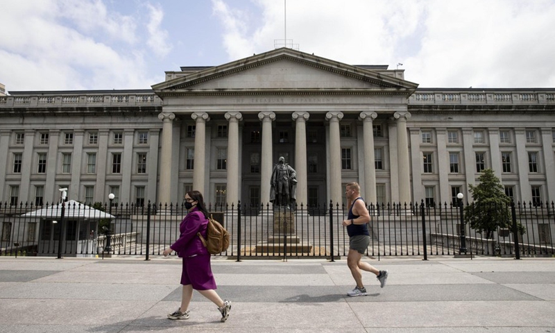 People walk past the US Treasury Department building in Washington, D.C., the United States, May 21, 2020. (Photo by Ting Shen/Xinhua)