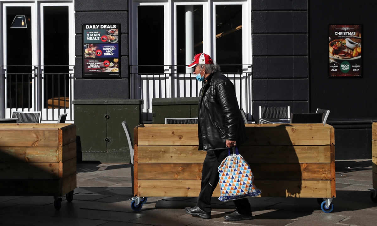 A man wearing a protective face mask walks past the Owain Glyndwr pub in Cardiff, south Wales on Sunday, during preparations for the reinstatement of a lockdown, ahead of a 6 pm deadline, as new restrictions are introduced to combat the spread of the novel coronavirus. Cardiff will become the first UK capital to go into local lockdown since a national shutdown earlier this year. 