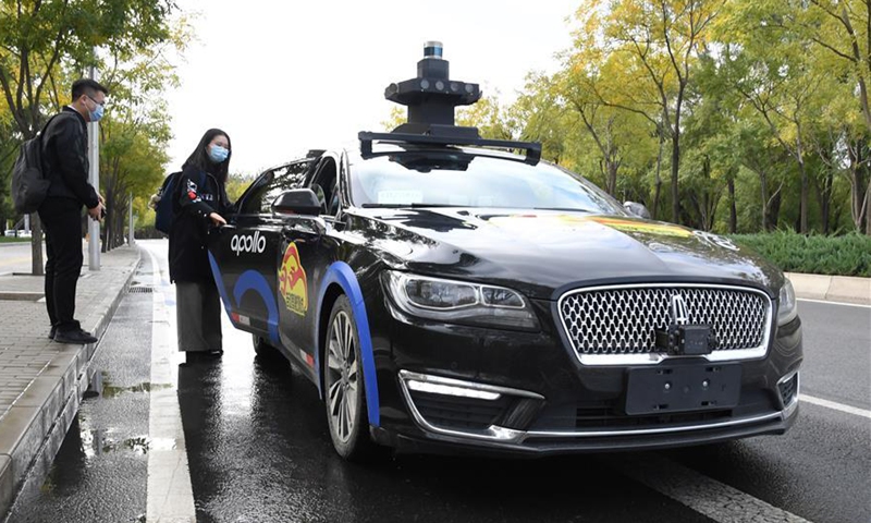 A woman takes a self-driving taxi at an appointed location on the Daoxianghu Road in Haidian District of Beijing, capital of China, Oct. 14, 2020. China's internet giant Baidu has launched a program in Beijing to offer free trials of its self-driving taxi service from Saturday. The pilot service, which serves certain stops in a part of the city from 10 a.m. to 4 p.m., will operate until Nov. 6, according to Baidu. (Xinhua/Ren Chao)
